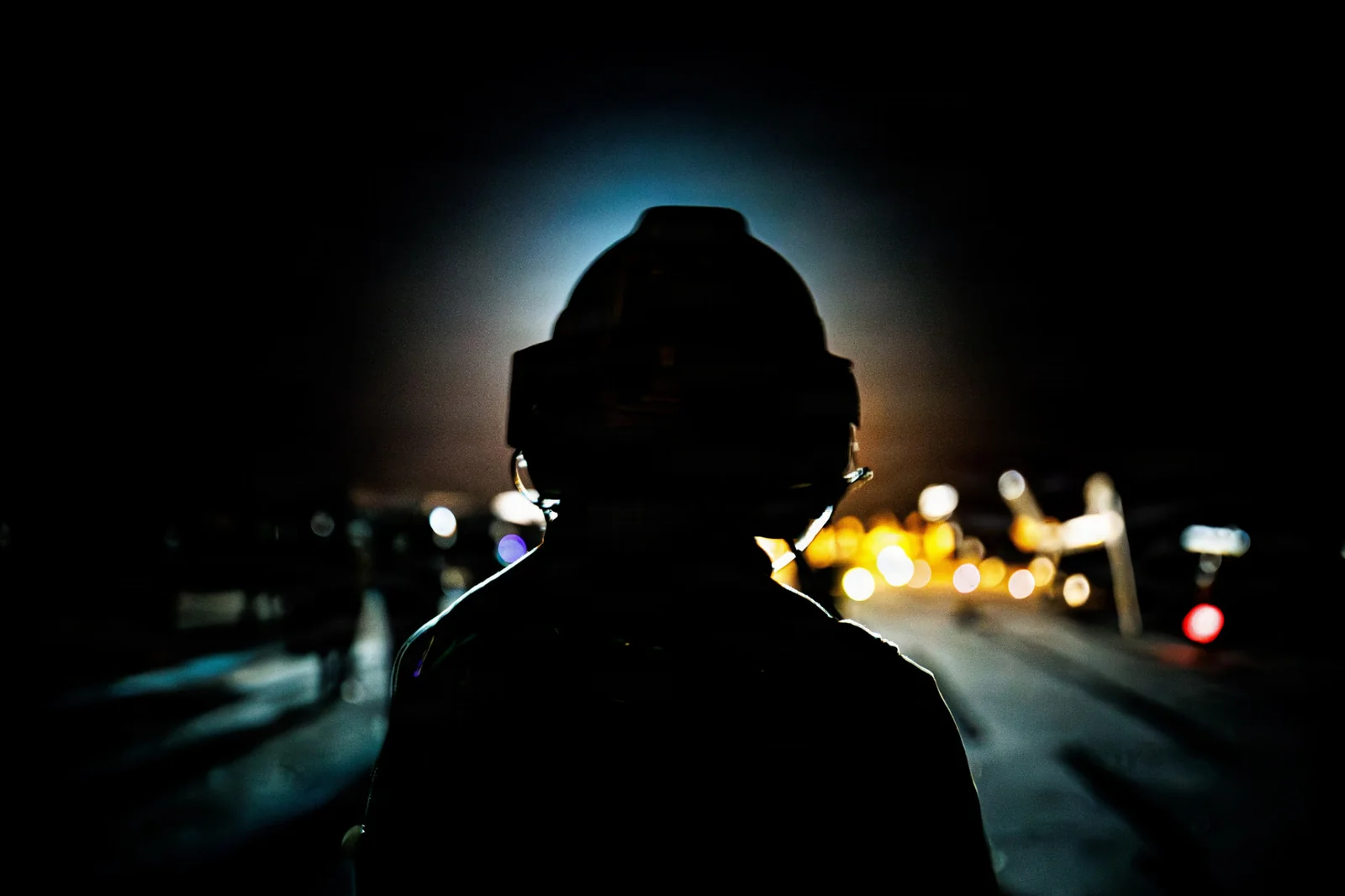 Helmeted crew member on a carrier flight deck at night